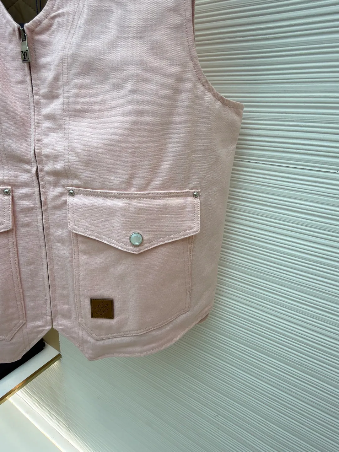 LOUIS Vuitton ●Description: This vest is made of high-quality cotton and linen blended fabrics, and the main tone of pink gives it a soft and fashionable feel. It has a V-neck design and a metal zipper placket, which is smooth and has industrial style details. The double patch pockets on the front chest have a three-dimensional structure, and the pockets are double-fastened with metal rivets and buttons to enhance practicality and decoration. A brand leather label is also embellished on the bottom of the bag to enhance recognition. The interior is quilted and the cotton batting is evenly distributed to ensure warmth and avoid clumping. The seams of the body are made of flat stitching + hemming technology, and the stitching is neat and firm, demonstrating exquisite workmanship. The overall shape is loose and moderate, combining the toughness of work clothes with the casualness of daily wear. From fabric selection to detail sewing, every craftsmanship takes into account both style expression and wearing experience. The overall wiring is straight and delicate, the fabric is comfortable and soft, and the color is consistent without color difference. It can be matched with the same style to create a fashionable look and control various occasions. Customized accessories, complete with three standards, same style for men and women!